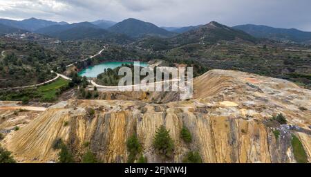 Colorful piles of copper mine tailings and lake in place of abandoned Memi mine in Xyliatos, Cyprus. Aerial landscape with distant mountains Stock Photo