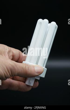 Man's hand holding compact fluorescent lamp. Close-up. Isolated on black. Stock Photo