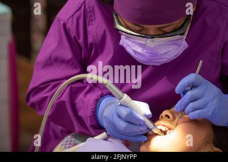A closeup of a Mexican female dentist doing dental treatment on the young girl Stock Photo