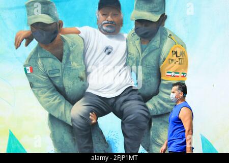 Man passing in front of a mural portraying the Covid-19 first responders  (in this mural: the soldiers) hailed as heroes in the fight against the pandemic , Merida Mexico Stock Photo