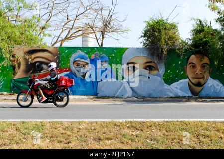 Motorcycle passing in front of a mural portraying the Covid-19 first responders hailed as heroes in the fight against the pandemic , Merida Mexico Stock Photo