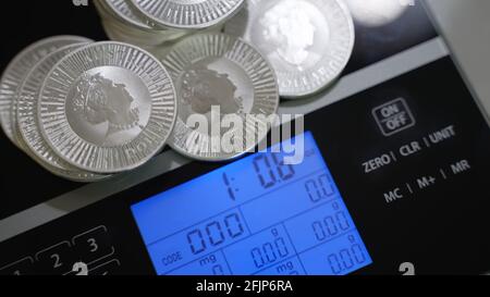 Silver investment coins weighing on precise digital scales. Money, investor and finance and economy concept.  Stock Photo