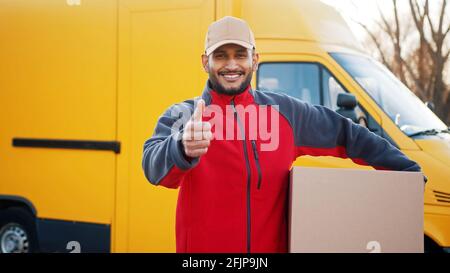 Smiling delivery man showing thumb up and looking at camera. High quality photo Stock Photo