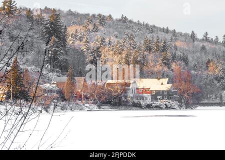Picturesque hillside town with houses and a red barn surrounded by snow covered trees Stock Photo