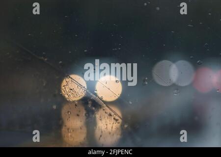 streaky rain drops on a car window with headlights Stock Photo