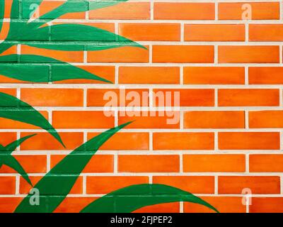 Brick wall background with green leaves painted. Empty space on vivid color brick wall texture. Stock Photo
