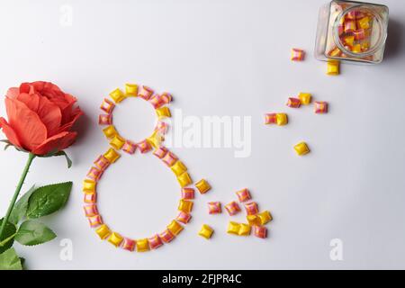 rose on a white background with bright candies from a jar in the form  Stock Photo