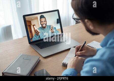 Back view of millennial man watching online training or course on laptop Stock Photo