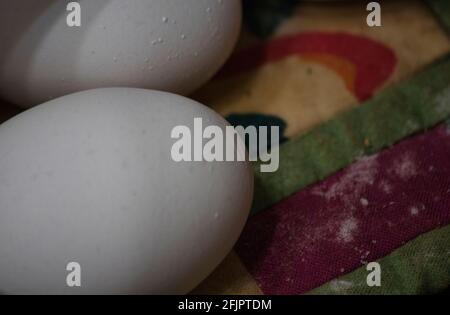 two whole white eggs set out on a quilted place mat Stock Photo