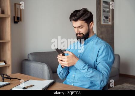 Millennial freelance businessman take break during workday using mobile phone Stock Photo