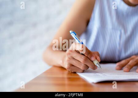 Close up hand of business women use pen writing document paper. Female hand close up writing with a blue pen on a white sheet. Woman writes informatio Stock Photo