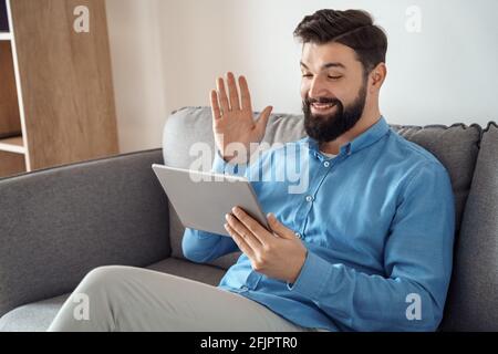 Smiling millennial caucasian man having video call chat on mobile tablet Stock Photo