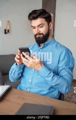 Millennial man blogger chatting online with followers using smartphone Stock Photo