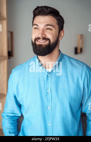 Indoor headshot portrait of smiling millennial man in good mood looking aside Stock Photo