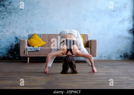 Master Yoga woman doing poses in the home, Prasarita Padottanasana. Stock Photo