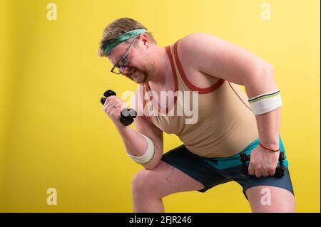 Funny overweight man flexing his muscle isolated on yellow background Stock Photo