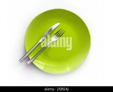Served plate with cutlery. Empty green plate and stainless knife and fork isolated on white background. Top view Stock Photo