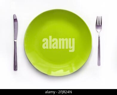 Served plate with cutlery. Empty green plate and stainless knife and fork isolated on white background. Top view Stock Photo
