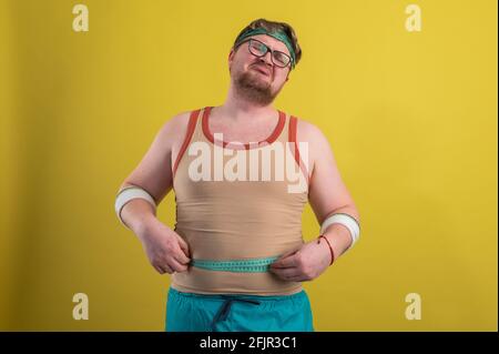 Funny overweight man flexing his muscle isolated on yellow background Stock Photo