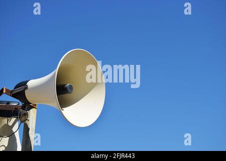 Old weathered vintage public address (PA) megaphone system loudspeaker and blue sky. Stock Photo