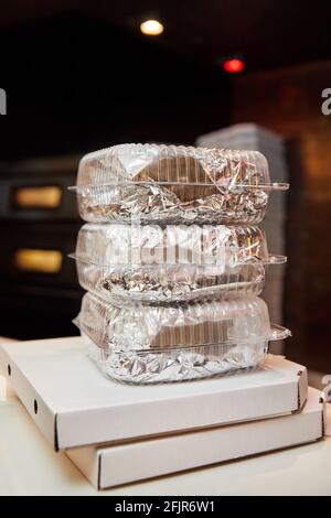 Stack of white closed cardboard pizza boxes and lunch boxes prepared for delivery. Close-up, selective focus Stock Photo