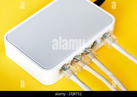 Ethernet cables connected to Desktop Switch or routerboard on a yellow background. Close-up, selective focus Stock Photo