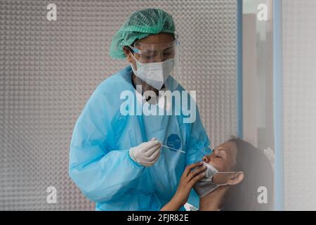 Bangkok, Thailand. 26th Apr, 2021. A medical staff f wearing a personal protective equipment suite (PPE) collects nasal swab sample from a woman at COVID-19 testing center. COVID-19 testing center at Thai-Japanese Bangkok Youth Center. (Photo by Varuth Pongsapipatt/SOPA Image/Sipa USA) Credit: Sipa USA/Alamy Live News Stock Photo