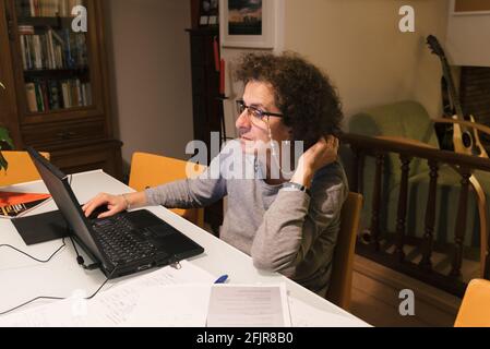 Businesswoman wearing glasses working on laptop computer sitting at home and managing her business. Home office concept during Coronavirus Stock Photo