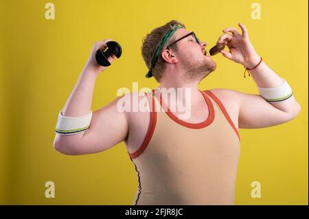 Funny overweight man flexing his muscle isolated on yellow background Stock Photo