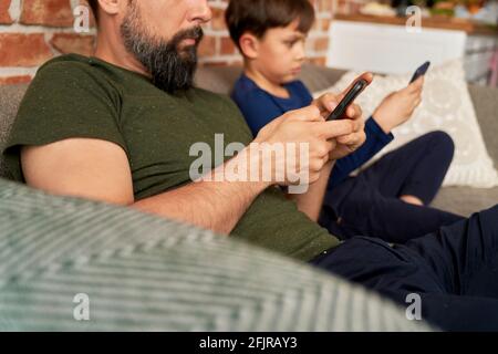 Close up side view of father and son using mobile phone Stock Photo