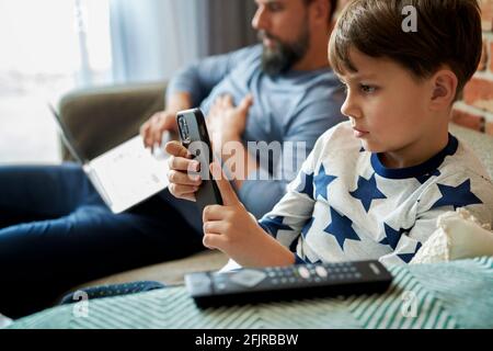 Close up of father working and son using mobile phone Stock Photo