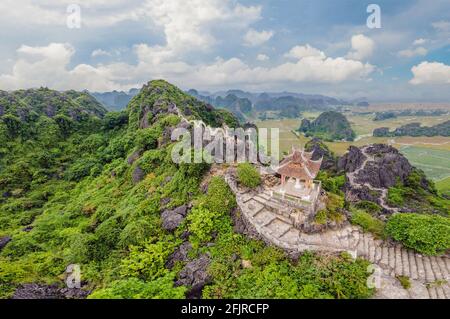 Family of tourists on the background of Amazing huge dragon statue at limestone mountain top near Hang Mua view point at foggy morning. Popular Stock Photo