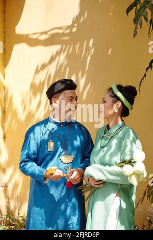 Young Vietnamese groom and bride standing outdoors and looking at each other with love and tender Stock Photo