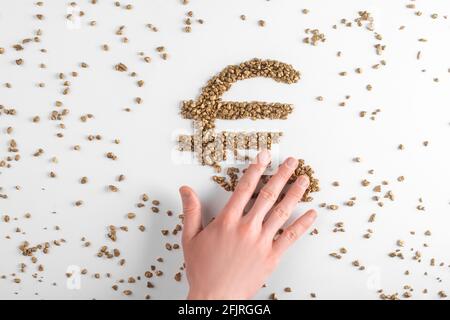 Hand sweeping euro sign made from golden pieces away, top view Stock Photo