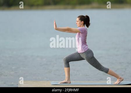 Side view portrait of a woman doing tai chi exercise in a lake pier on summer Stock Photo