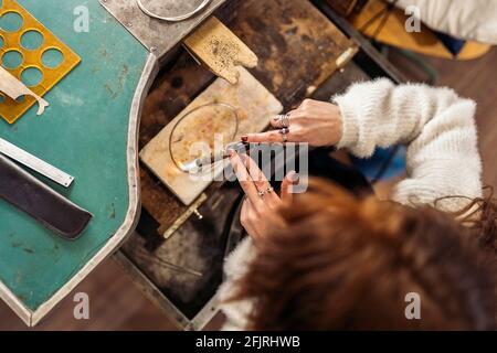 Stock photo of faceless woman using blowtorch in jewelry workshop. Stock Photo