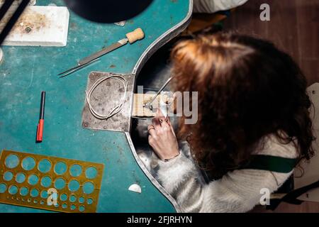 Stock photo of faceless woman working in jewelry workshop. Stock Photo