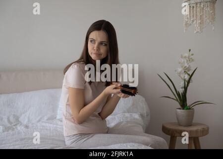 Annoyed worried young millennial woman with comb founding Stock Photo