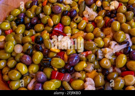 Mixed pickled black and green Olives with vegetables at the weekly market in french province. Background of marinated vegetables in a bowl, close up. High quality photo Stock Photo