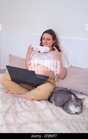 Happy pregnant woman takes off face mask after quarantine and pandemic ends Stock Photo
