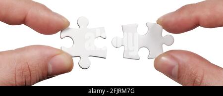 Close up Connection. Hands trying to fit two puzzle pieces together. Hands trying to attach two jigsaw puzzle pieces isolated on white Stock Photo