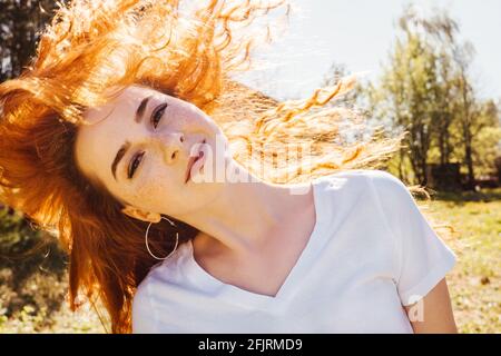Young happy woman with flying long curly hair in sunshine. Stock Photo