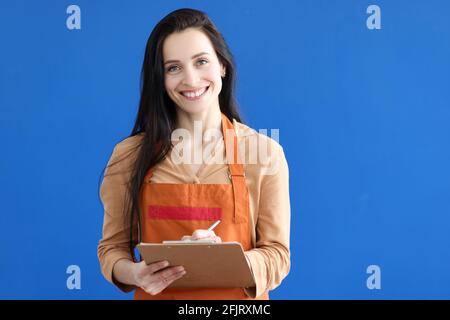 Woman waiter writing down order on blue background Stock Photo