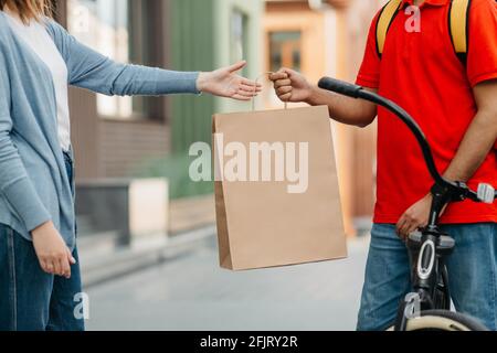 Male courier with bicycle delivered no name shopping bag to client and food service at home Stock Photo