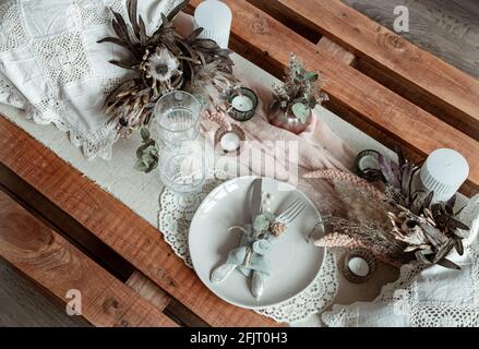 Romantic table setting with candles and dried flowers for a wedding or Valentine's Day. Stock Photo