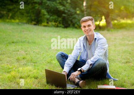 Smiling student guy using laptop computer at university campus Stock Photo