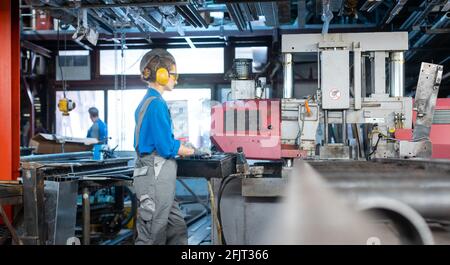 Woman worker operating a machine tool in metal workshop or factory Stock Photo
