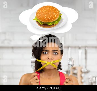 Weight loss concept. African American woman with measuring tape around her mouth dreaming about unhealthy burger