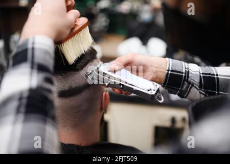 Rear view of man client visiting haidresser in barber shop. Stock Photo