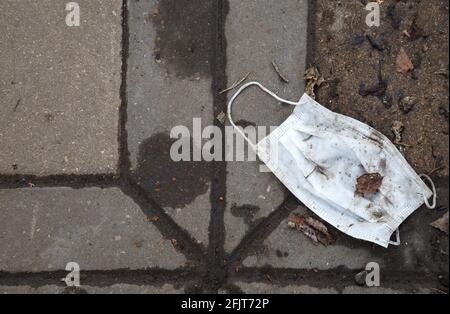 Photo of throwed used medical mask on the cobblestone Stock Photo